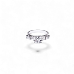 Anillo AVA & SSILAQUÉ de oro blanco de 14 quilates con un diamante radiante cuadrado central de 1 quilate y diamantes laterales princesa y trapecio.