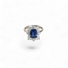 Anillo de oro blanco de 14K de AVA & SSILAQUÉ con zafiro azul cojín central rodeado de diamantes de laboratorio en talla marquesita y redonda.