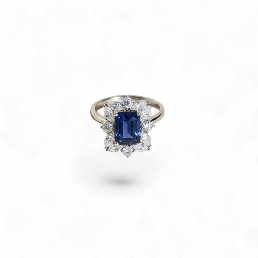 Anillo de oro blanco de 14K de AVA & SSILAQUÉ con zafiro azul cojín central rodeado de diamantes de laboratorio en talla marquesita y redonda.